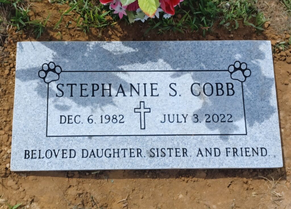 Single flat grave marker in granite with custom engraving, set flush to the ground in a peaceful cemetery setting.