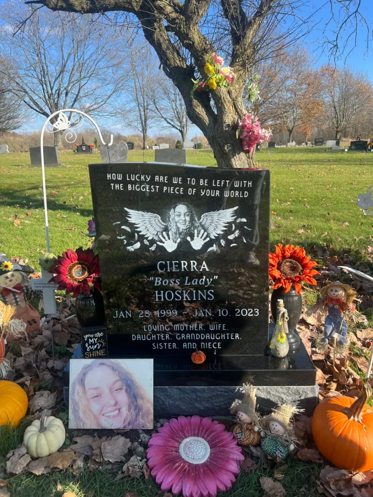 Single upright granite monument with individual name engraving in a quiet cemetery landscape.