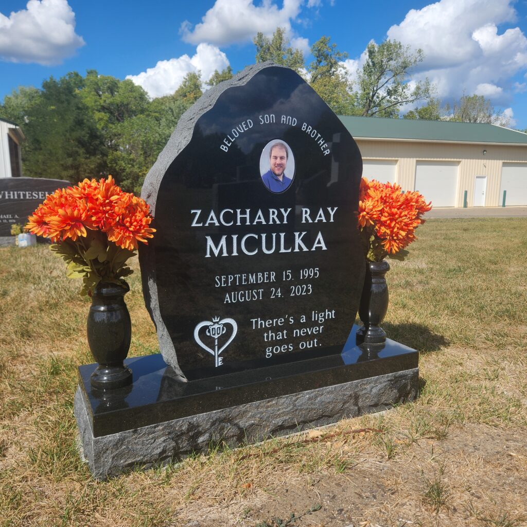 Single upright granite monument with elegant design and custom engraving, standing as a timeless tribute in a beautifully landscaped cemetery.