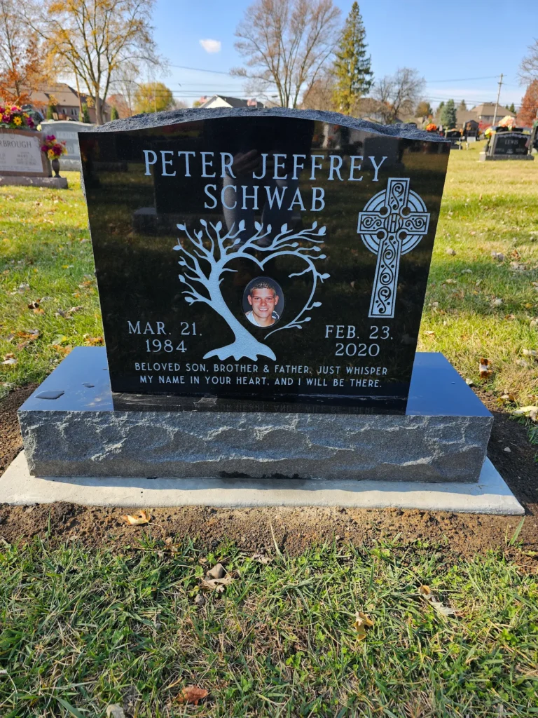 Single upright monument headstone in polished granite with personalized engraving, standing tall as a lasting tribute in a serene cemetery.