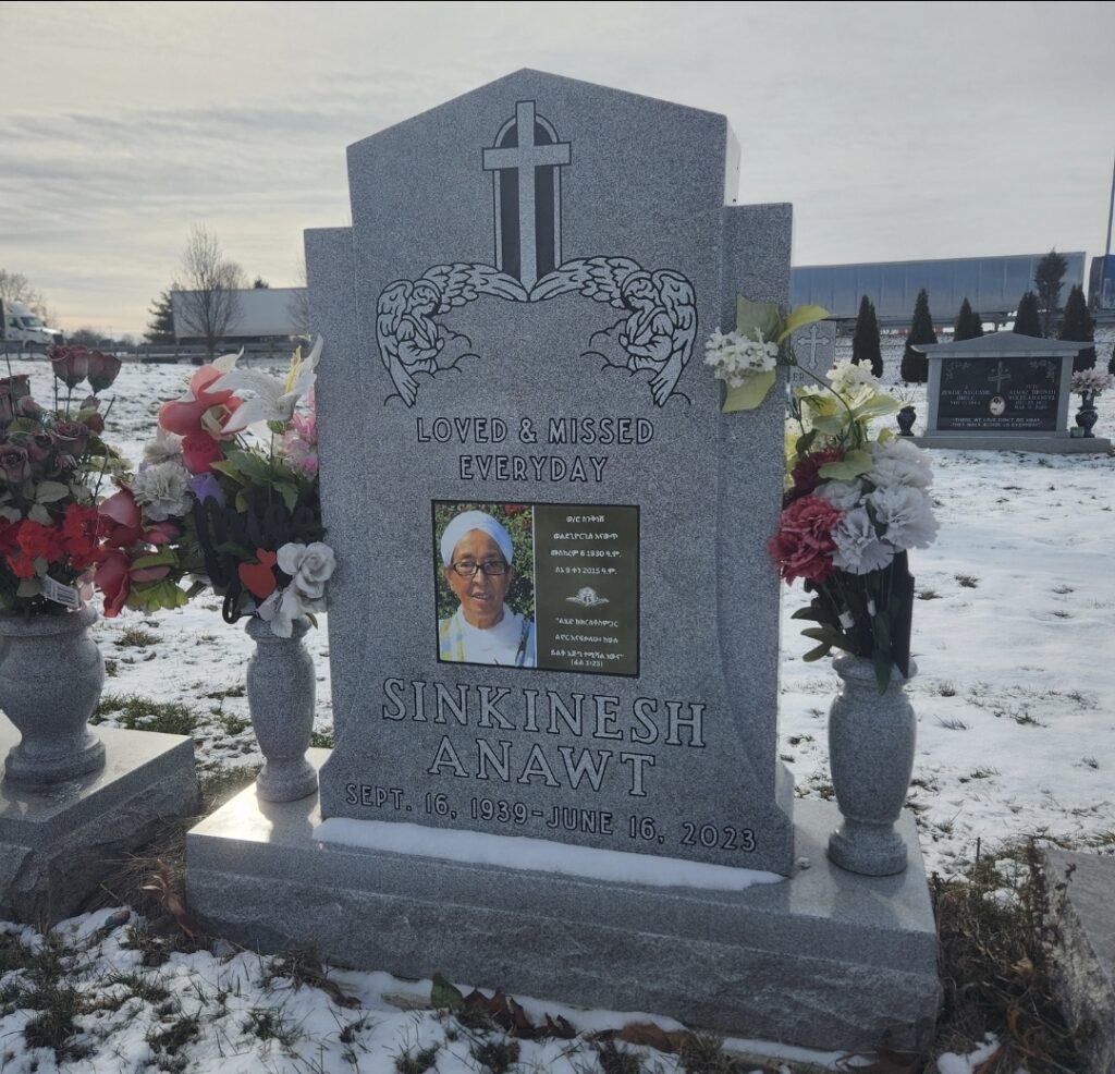 Single upright granite monument with finely detailed engraving, offering a timeless and dignified memorial in a peaceful cemetery setting.