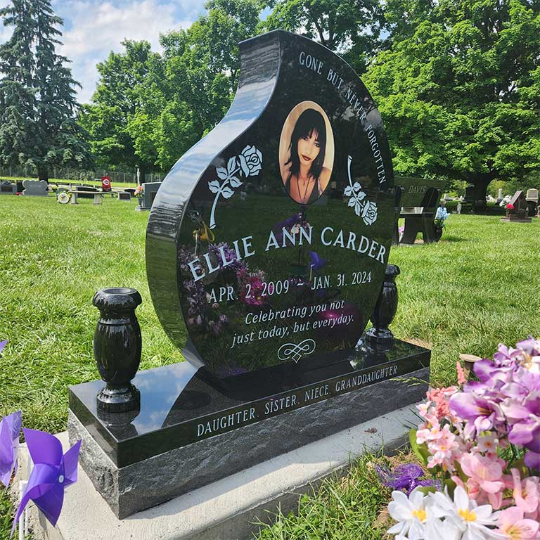 A custom-shaped granite memorial with a unique heart silhouette and artistic engraving, designed by Stoltz Memorials in Dublin, Ohio.