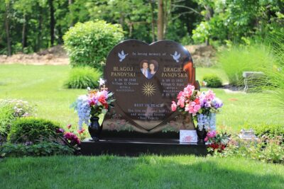 A finished elegant companion slant headstone made of grey granite, professionally set on a concrete foundation in a cemetery.