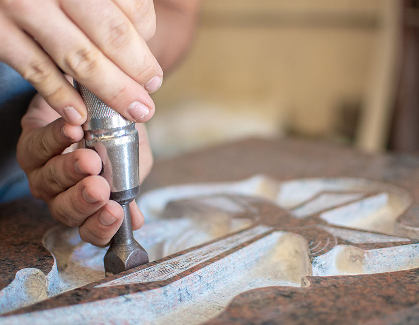A skilled craftsman engraving a custom design onto a granite headstone for a grave in [City], Ohio, demonstrating the quality and depth of Stoltz Memorials' carving.